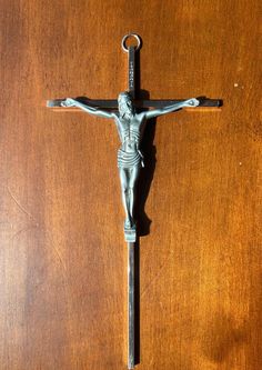 a crucifix on a wooden surface with a metal cross hanging from it's side