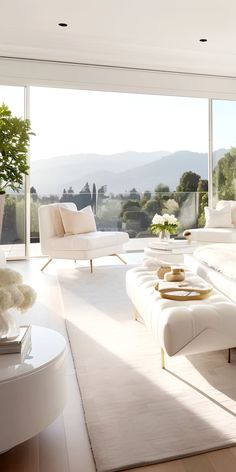 a living room filled with white furniture and large windows overlooking the mountains in the distance