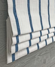 four blue and white striped curtains hanging on a gray wooden wall next to a wood floor