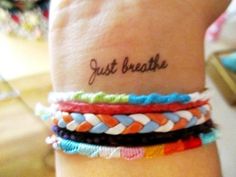 a woman's wrist with four different bracelets on it and the words just breathe written in cursive writing