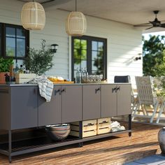 an outdoor kitchen on a wooden deck with chairs and potted plants in the background