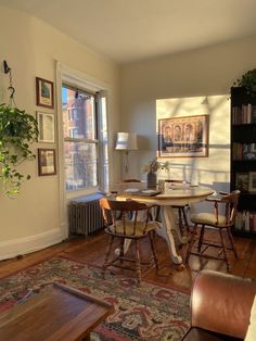 a living room filled with furniture next to a table and bookshelf on top of a hard wood floor