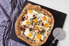 an egg and bacon pizza on a black tray