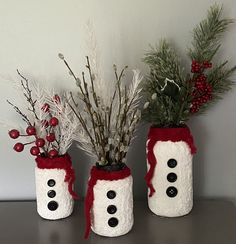 three snowman jars decorated with red and white yarn, one has a black nose