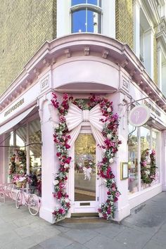 a pink store front decorated with flowers and ribbons