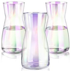 three glass vases sitting next to each other on a white surface with one filled with water