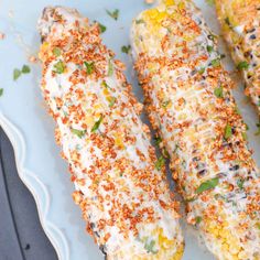 three corn on the cob covered in cheese and seasoning