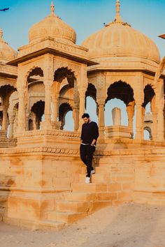 a man is standing on some steps in front of a building with arches and pillars