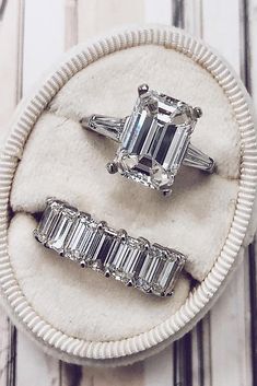 three diamond rings sitting on top of a white cloth ring box with two diamonds in the middle