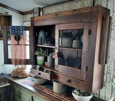 an old fashioned kitchen cabinet with pots and pans on the top, next to a potted plant