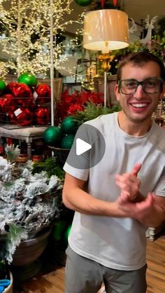 a man is standing in front of christmas decorations and giving the peace sign with his hands