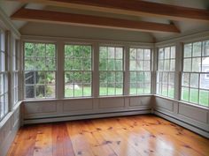 an empty room with wood floors and windows