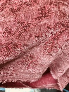 the fabric is pink and has an intricate design on it, as well as some other things