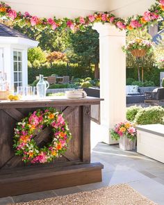 an outdoor bar decorated with flowers and wreaths on the front porch, next to a gazebo