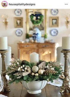 a white bowl filled with christmas decorations on top of a wooden table next to candles