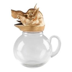 a glass teapot with a gold leaf on top and a white cup in the shape of a fish