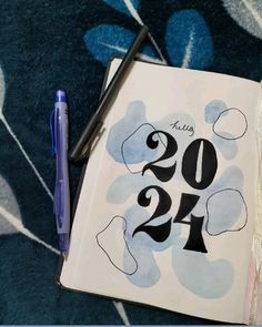 an open notebook with the numbers twenty and twenty on it next to a blue pen