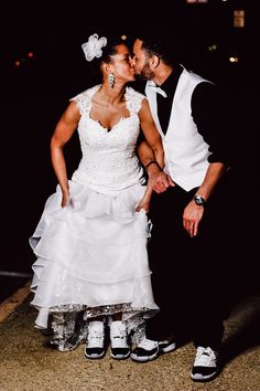 a bride and groom kissing in front of the camera at night with their shoes on