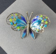 Very sweet spun silver butterfly brooch marked 800 on the reverse, He is made of spun silver and displays gorgeous enamel in bright shades of blue and green. Height:   1 inch Width:     1  5/8 inches In very good vintage condition! Collectible Hallmarked Blue Brooches, Blue Enamel Brooch Gift, Blue Enamel Brooch For Gift, Multicolor Butterfly Brooch Jewelry, Blue Enamel Brooches For Gift, Silver Enamel Brooch Pin, Butterfly-shaped Enamel Pin Gift, Butterfly Shaped Enamel Pin For Gifts, Silver Enamel Pin For Wedding