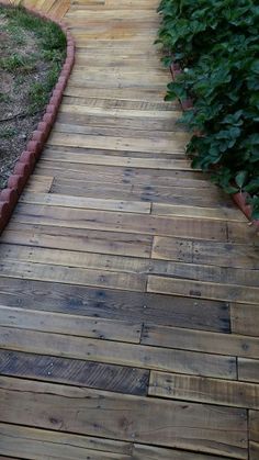 a wooden walkway in the middle of a garden