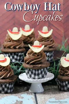 cupcakes with chocolate frosting and straw hats on top are sitting in the grass