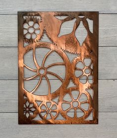 a piece of metal art that looks like gears and wheels on wood planks with white boards in the background