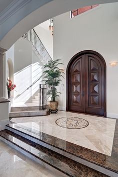 a large foyer with marble steps and wooden doors