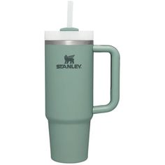 the stanley travel mug is mint green with a white lid and handle that holds a straw in it