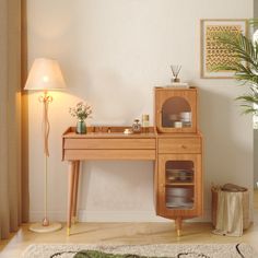 a wooden desk with a birdcage on it in front of a lamp and potted plant