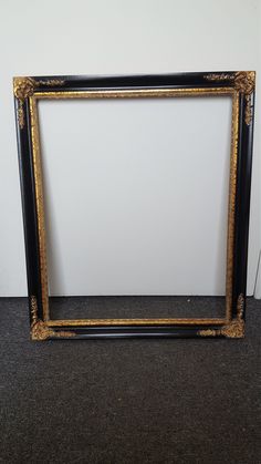 an old black and gold frame sitting on the floor