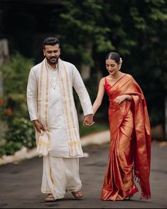 a man and woman holding hands while walking down the street