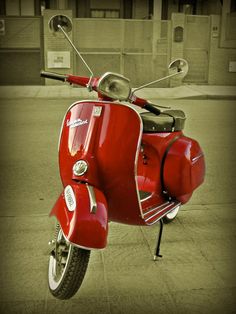 a red scooter is parked on the sidewalk