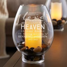 a glass vase filled with rocks on top of a wooden table next to a candle