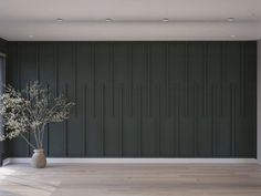 a vase with some flowers in it sitting on the floor next to a wall that is painted dark green