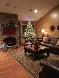 a living room filled with furniture and a christmas tree in front of a fire place