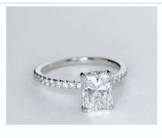 a white gold engagement ring with a princess cut diamond and pave set diamonds around the band