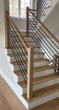 a wooden staircase with metal handrails in an empty room next to a window