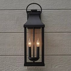 an outdoor wall light with three candles on it