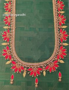 an elaborate necklace with red and gold beads on green fabric, in the shape of a flower