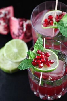 two glasses filled with pomegranate, lime and mint garnishes