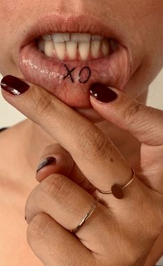 a woman is holding her tongue with the word x on it