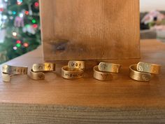 five gold rings sitting on top of a wooden table next to a christmas tree with lights in the background