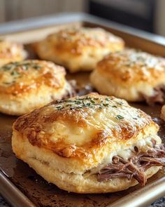 some biscuits with meat and cheese are on a baking sheet