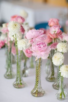 several vases filled with pink and white flowers on top of a cloth covered table