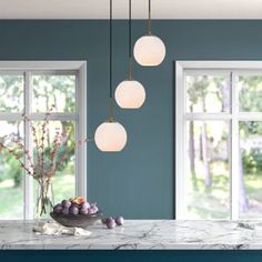 a kitchen with blue walls and marble counter tops, three lights hanging from the ceiling