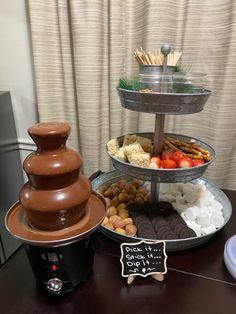 three tiered trays filled with food on top of a table next to a sign