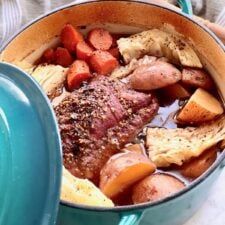 a pot filled with meat and vegetables on top of a table next to a person