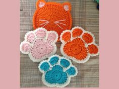 three crocheted coasters with cats and paw prints on the top one has an orange cat's head