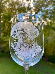 a wine glass sitting on top of a green grass covered field with trees in the background