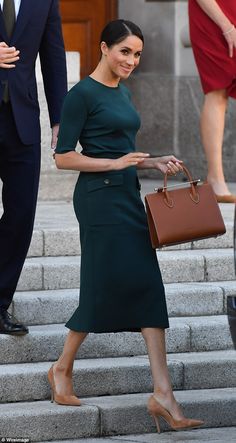 a woman in a green dress is walking down the steps with a brown bag and shoes